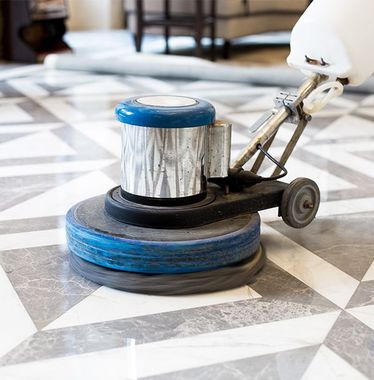 A machine is cleaning a marble floor in a room.