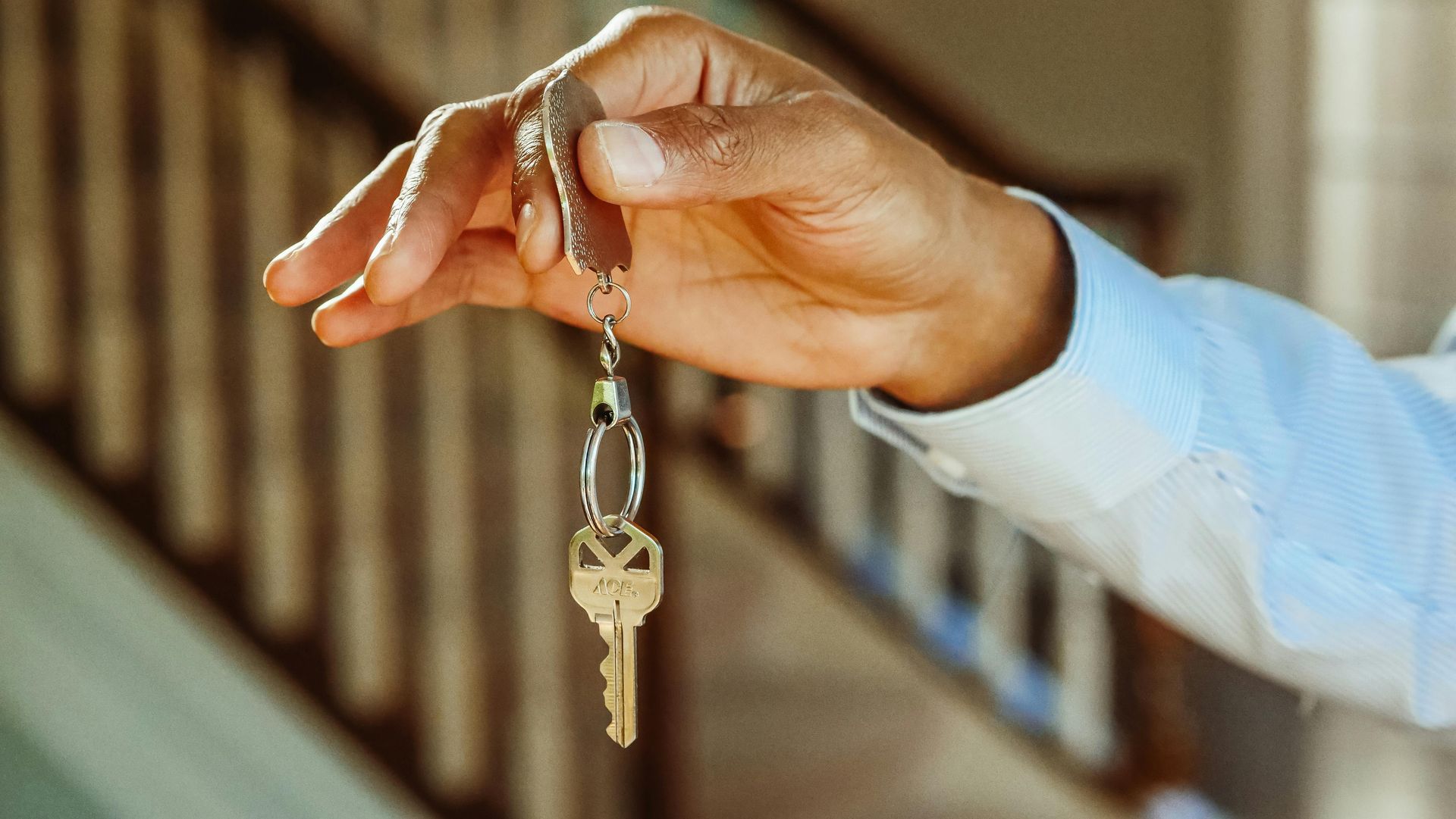 A hand, holding a keyring with a key hanging off of it