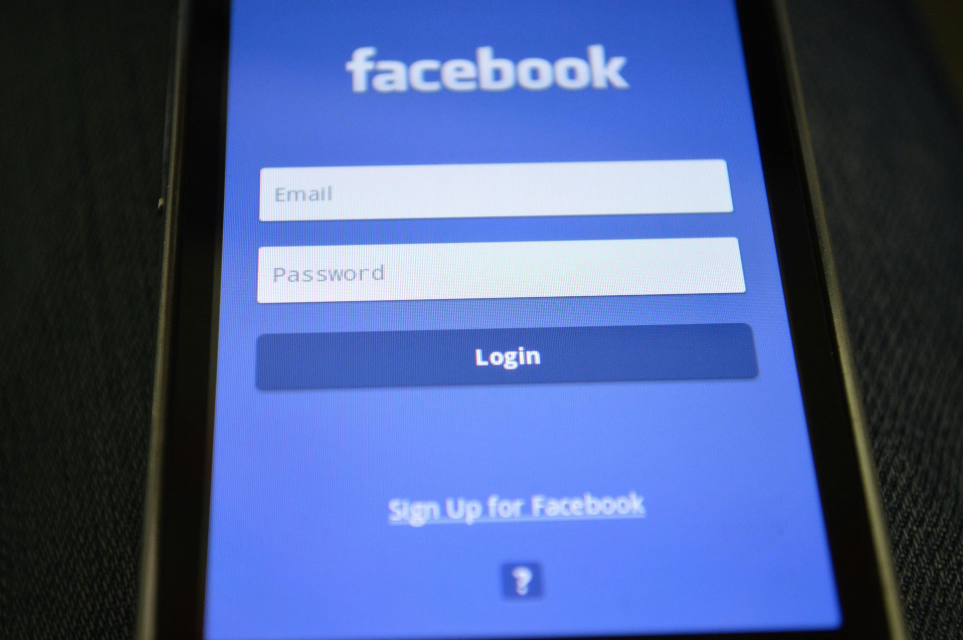 Facebook login screen on a smartphone, blue and white, with email and password fields, and 