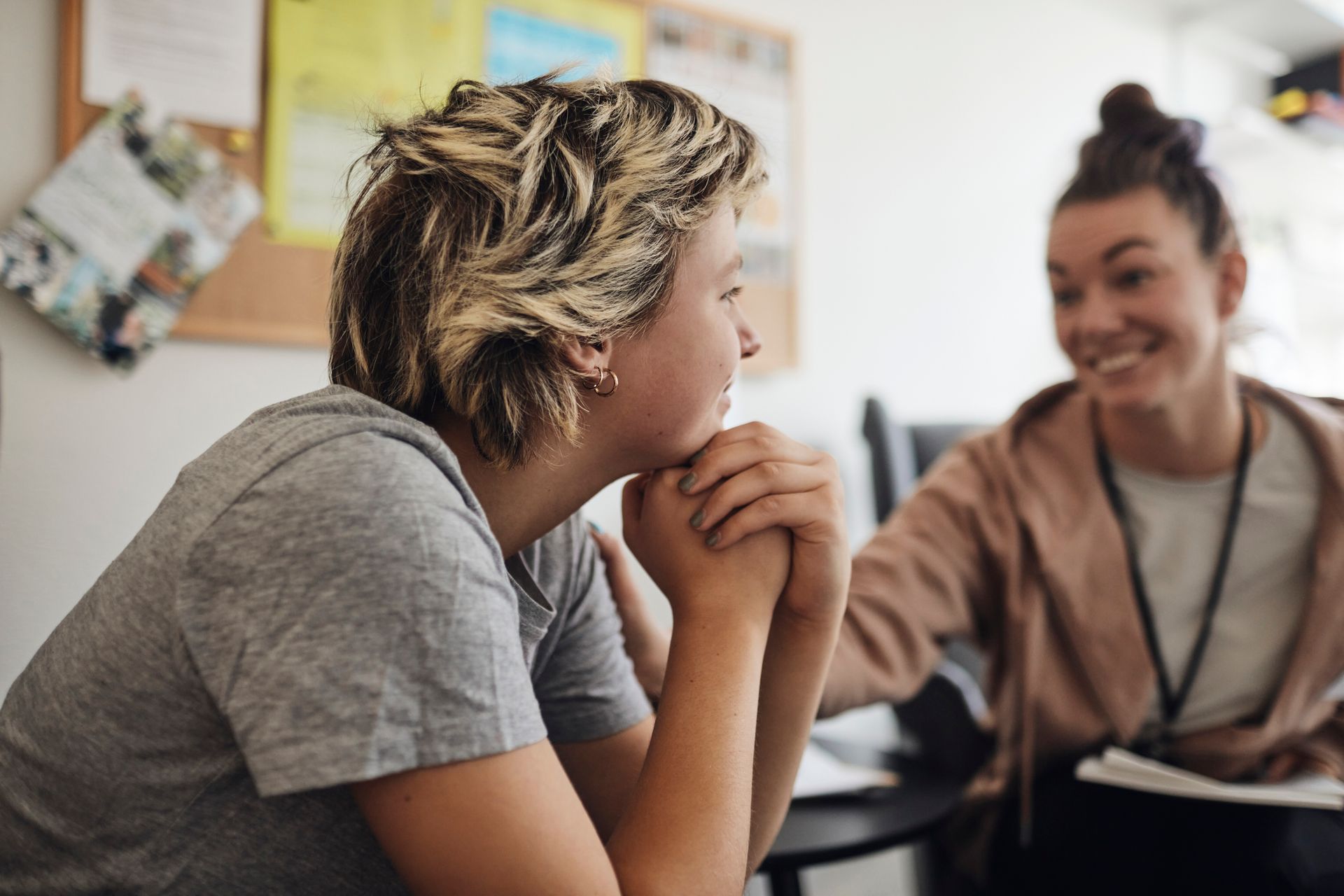 Teenager in counseling session, listening intently, smiling counselor.