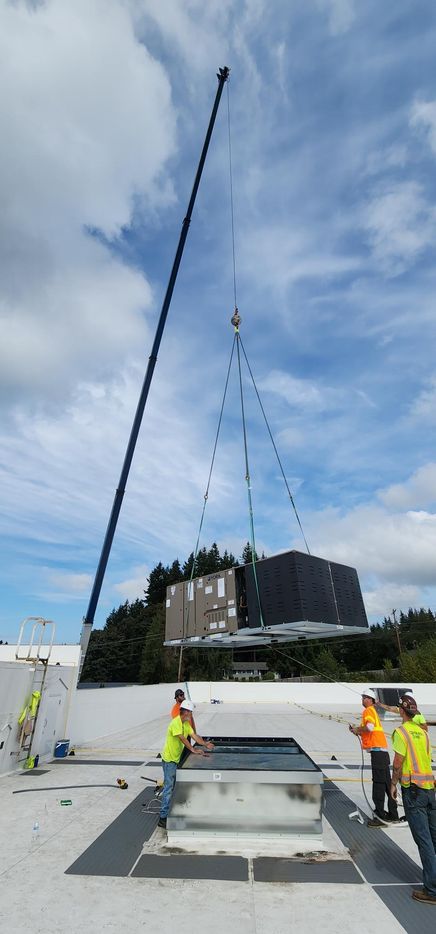 A group of construction workers are working on a roof with a crane.