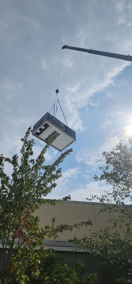 A crane is lifting a box into the air.