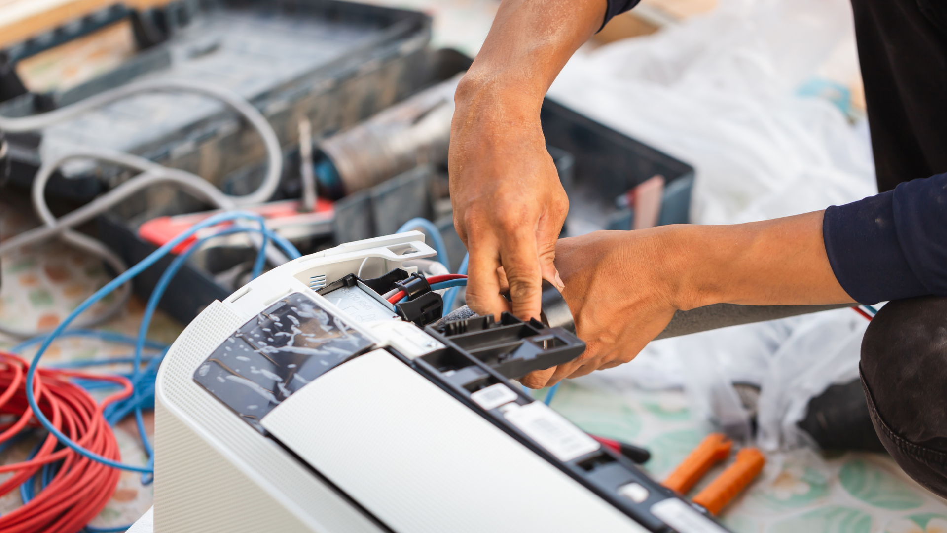 A man is fixing an air conditioner on the floor.