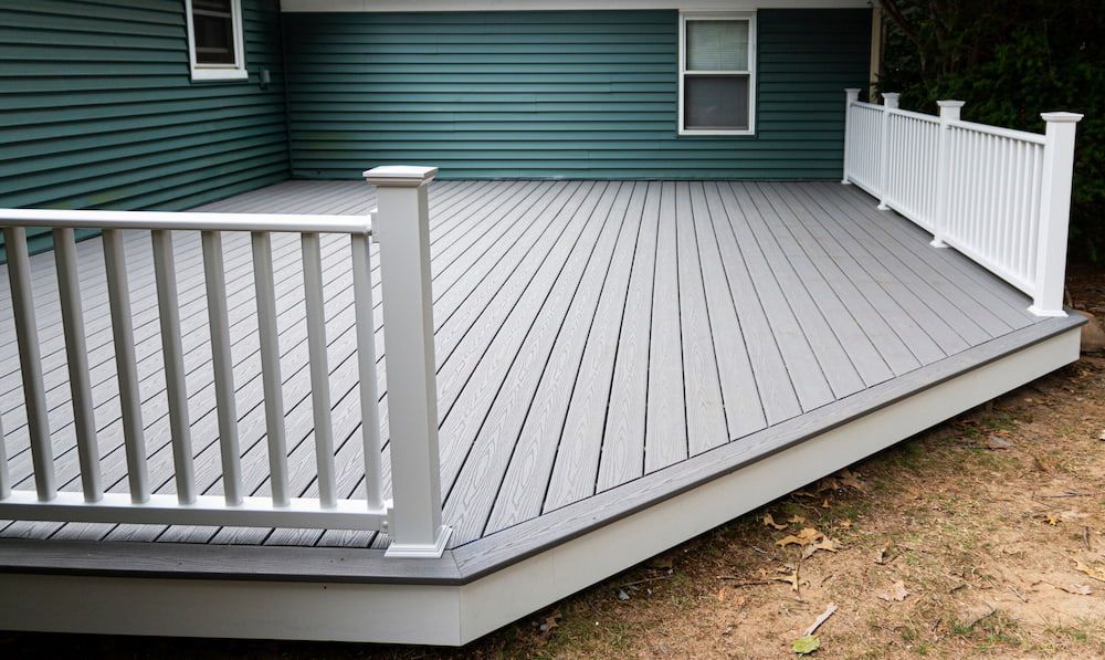 A Gray Deck With A White Railing Is In Front Of A Green House — Greg Pollard Building In Banora Point, NSW