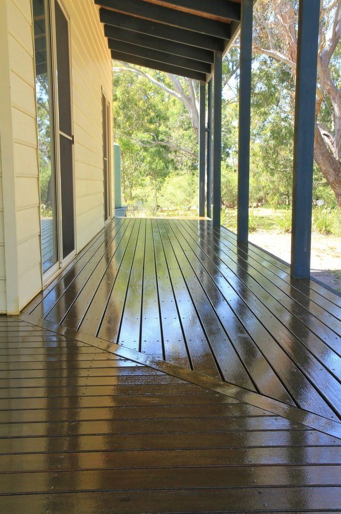 A Wooden Deck With A Covered Porch And Trees In The Background — Greg Pollard Building In Bogangar, NSW