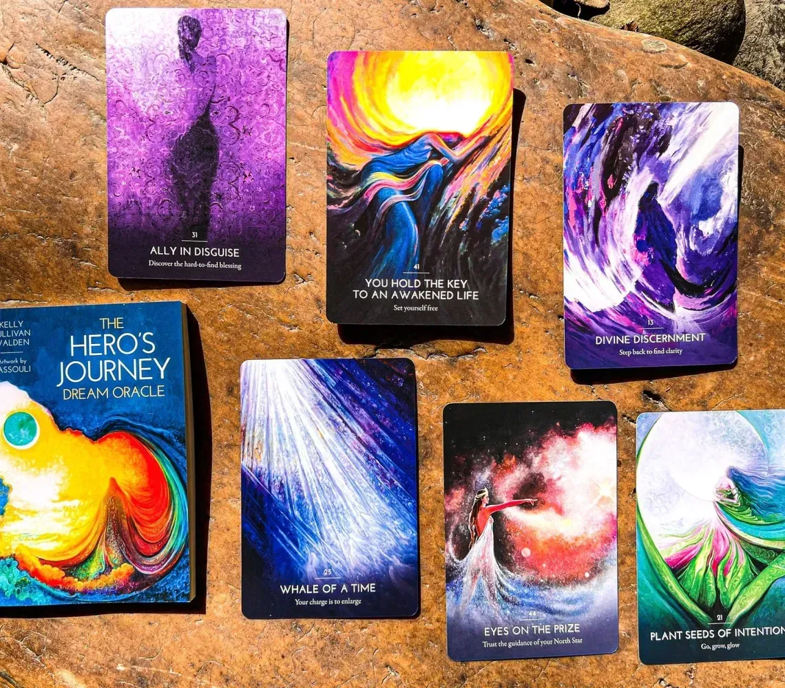 Seven colorful tarot cards arranged on stone, featuring bright abstract cosmic and nature-themed artwork.