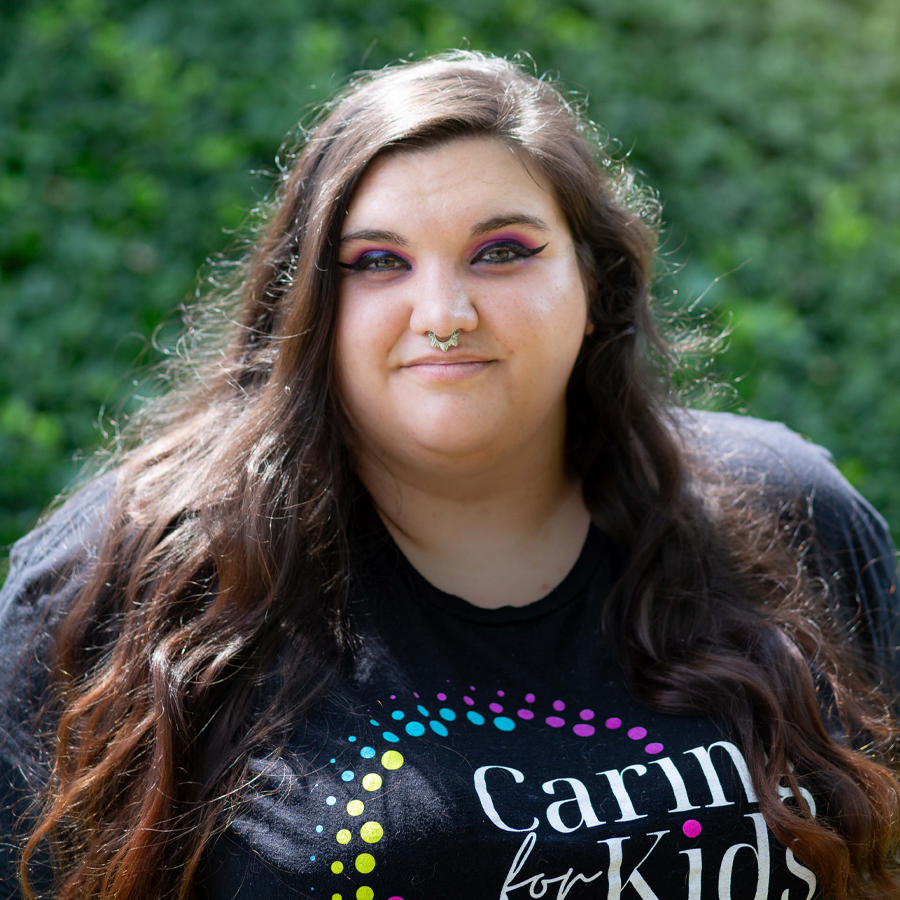 Woman with long brown hair, nose ring, wearing a black shirt with 