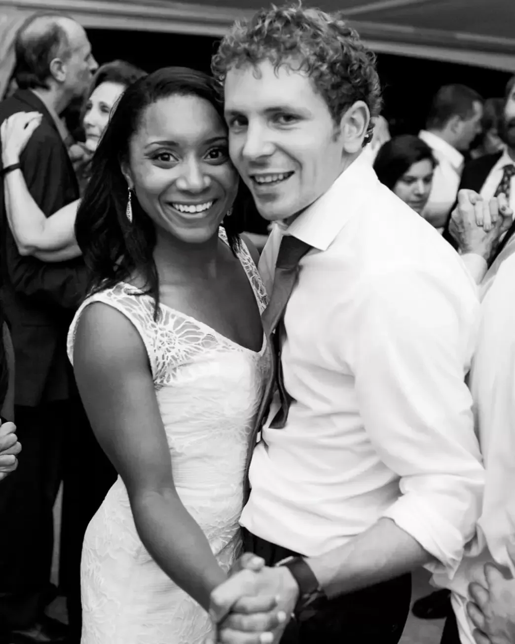 Bride and groom dancing at wedding reception, smiling. Black and white.
