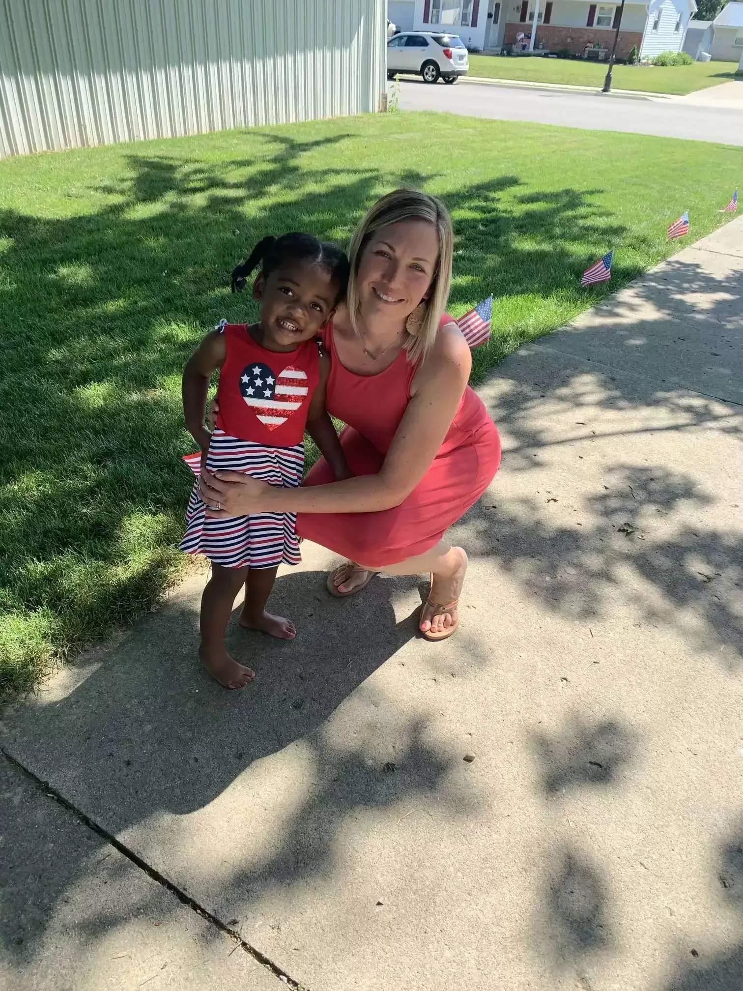 Woman and child smiling, outside. Child in patriotic outfit, woman in red dress.
