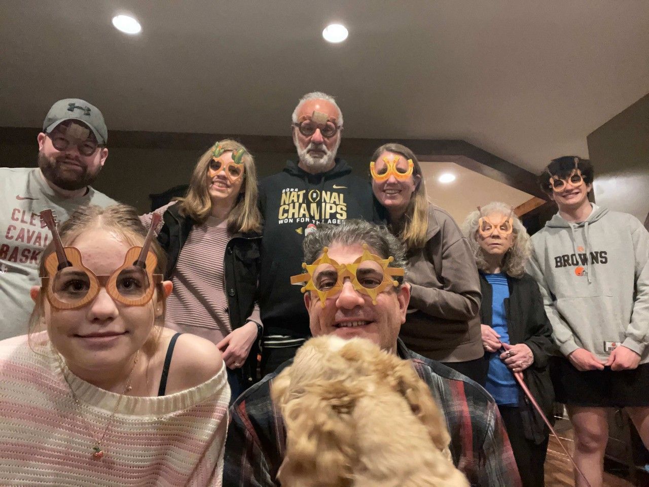 Family group with silly glasses, posing indoors with a dog.