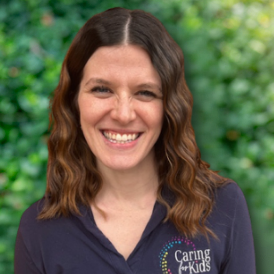 Smiling woman with brown hair in a denim shirt, looking at the camera.