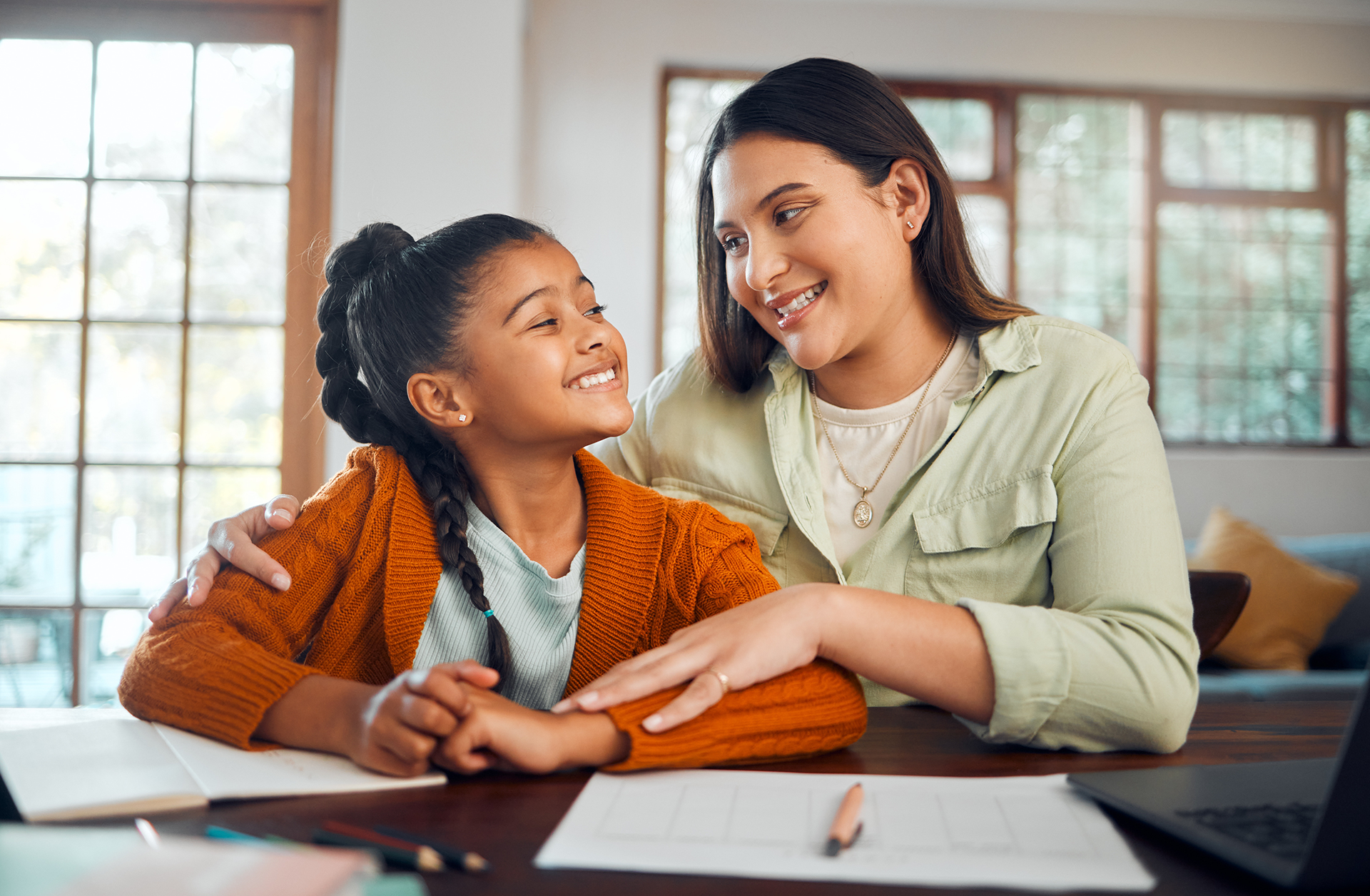Woman and boy packing luggage together, smiling. Yellow top, white shirt, indoor setting.