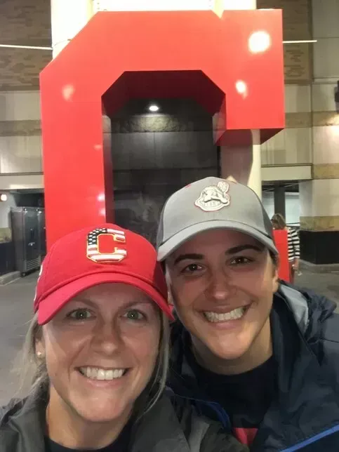 Two women smiling in front of a giant red