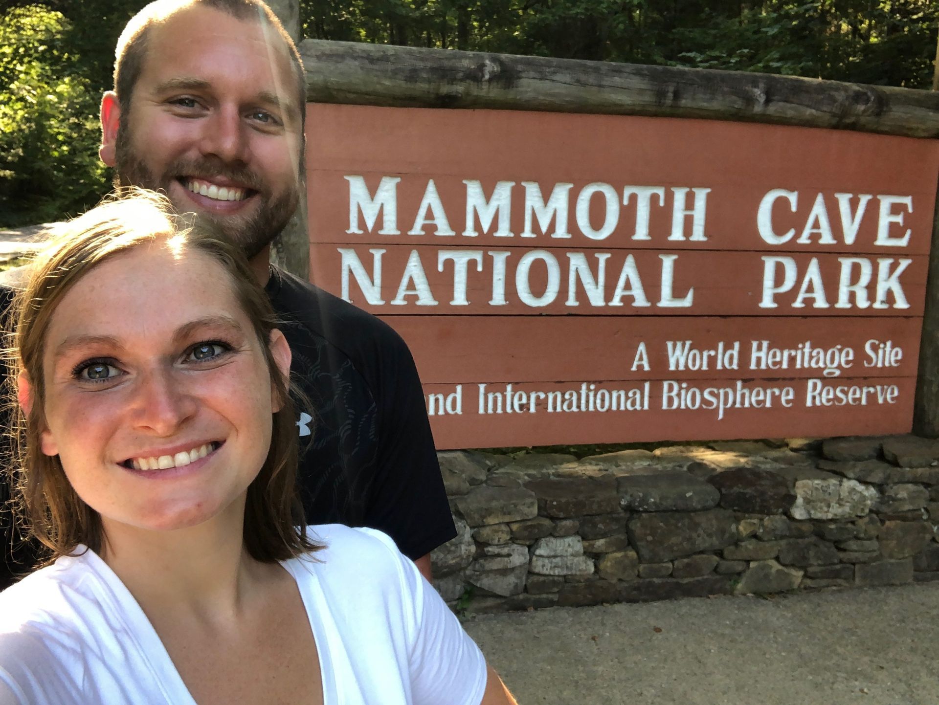 Couple smiling in front of the Mammoth Cave National Park sign.