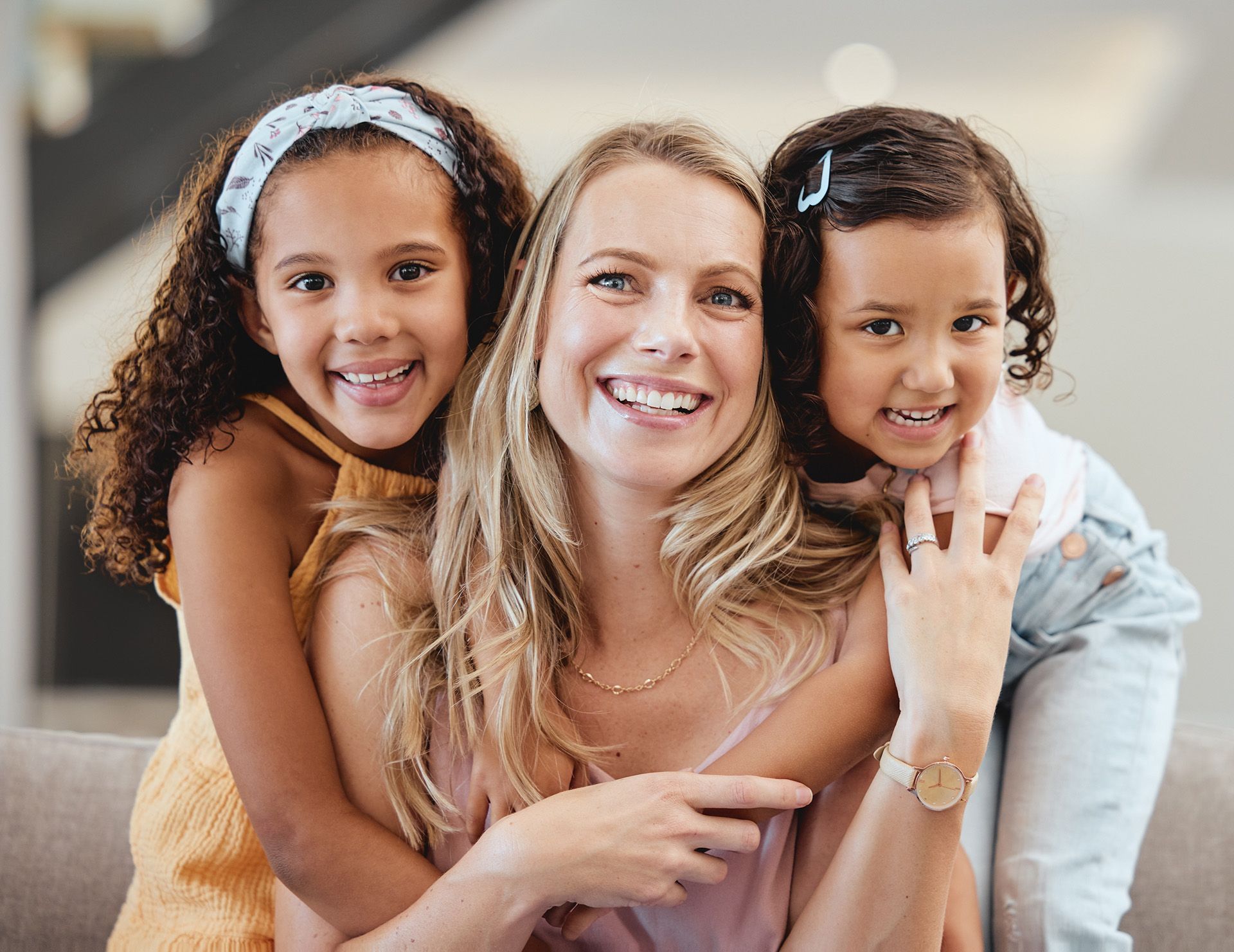 Woman with two young girls smiling, embracing.