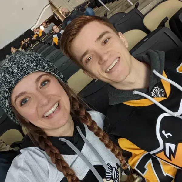 Couple smiling at a hockey game, wearing team jerseys and winter hat.