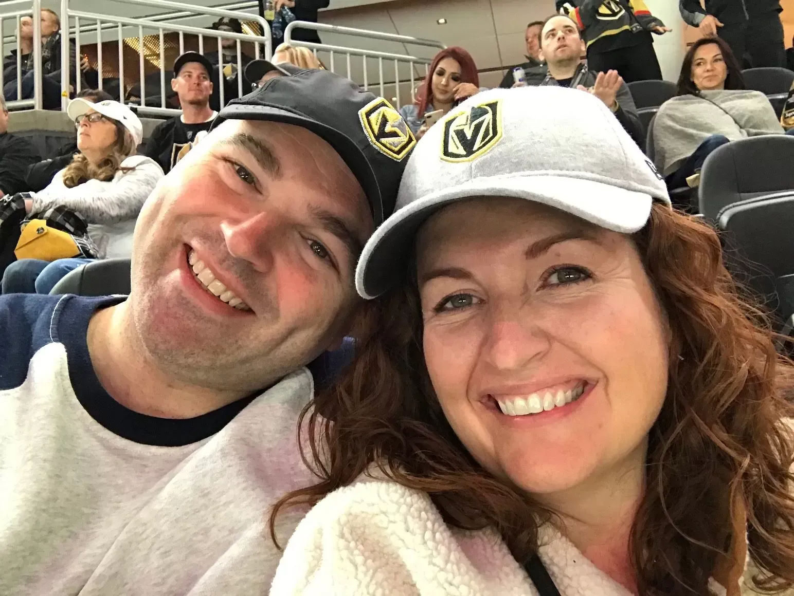 Smiling couple wearing Vegas Golden Knights hats at a hockey game.