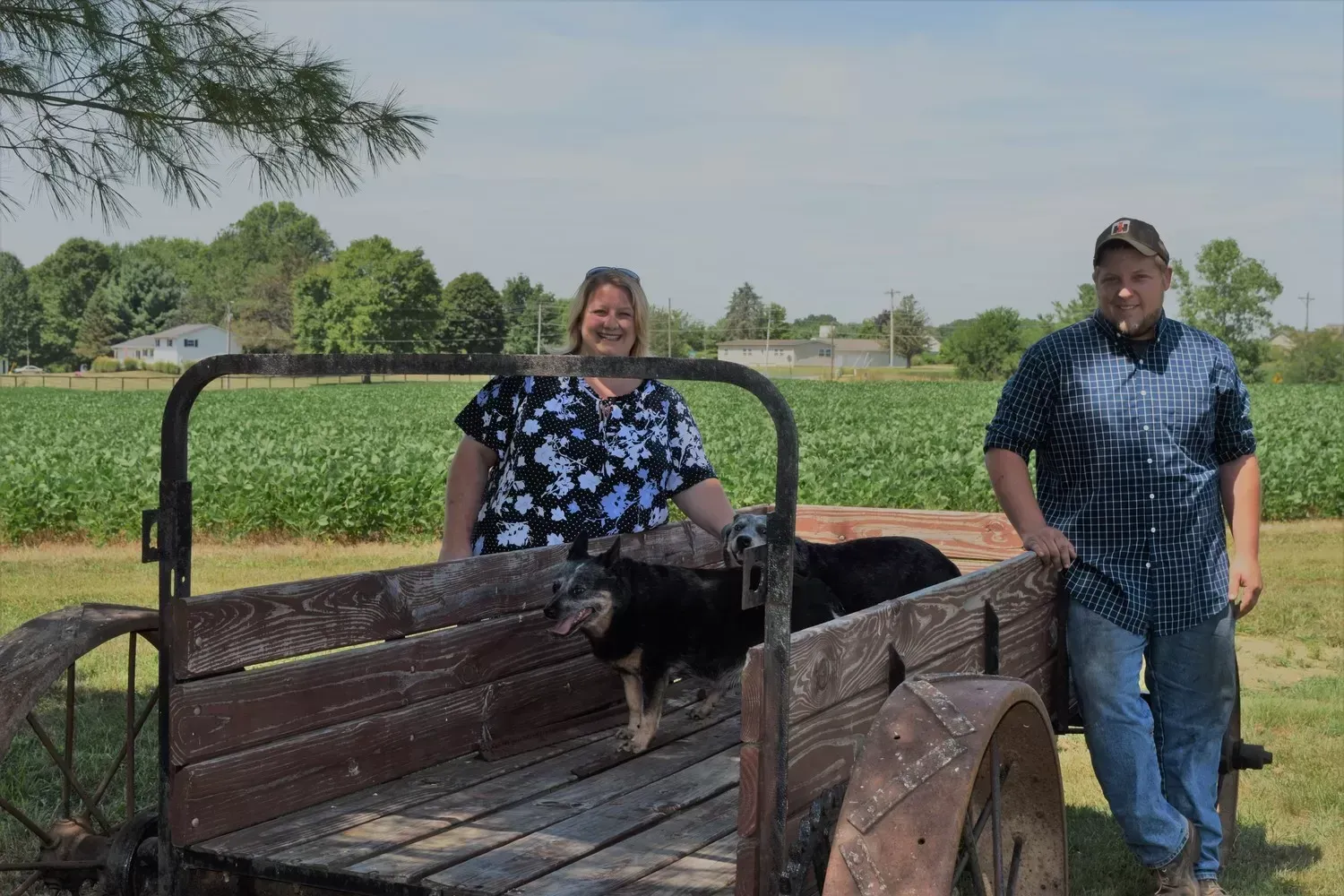 Woman and man with a dog in an old wooden cart on a farm.
