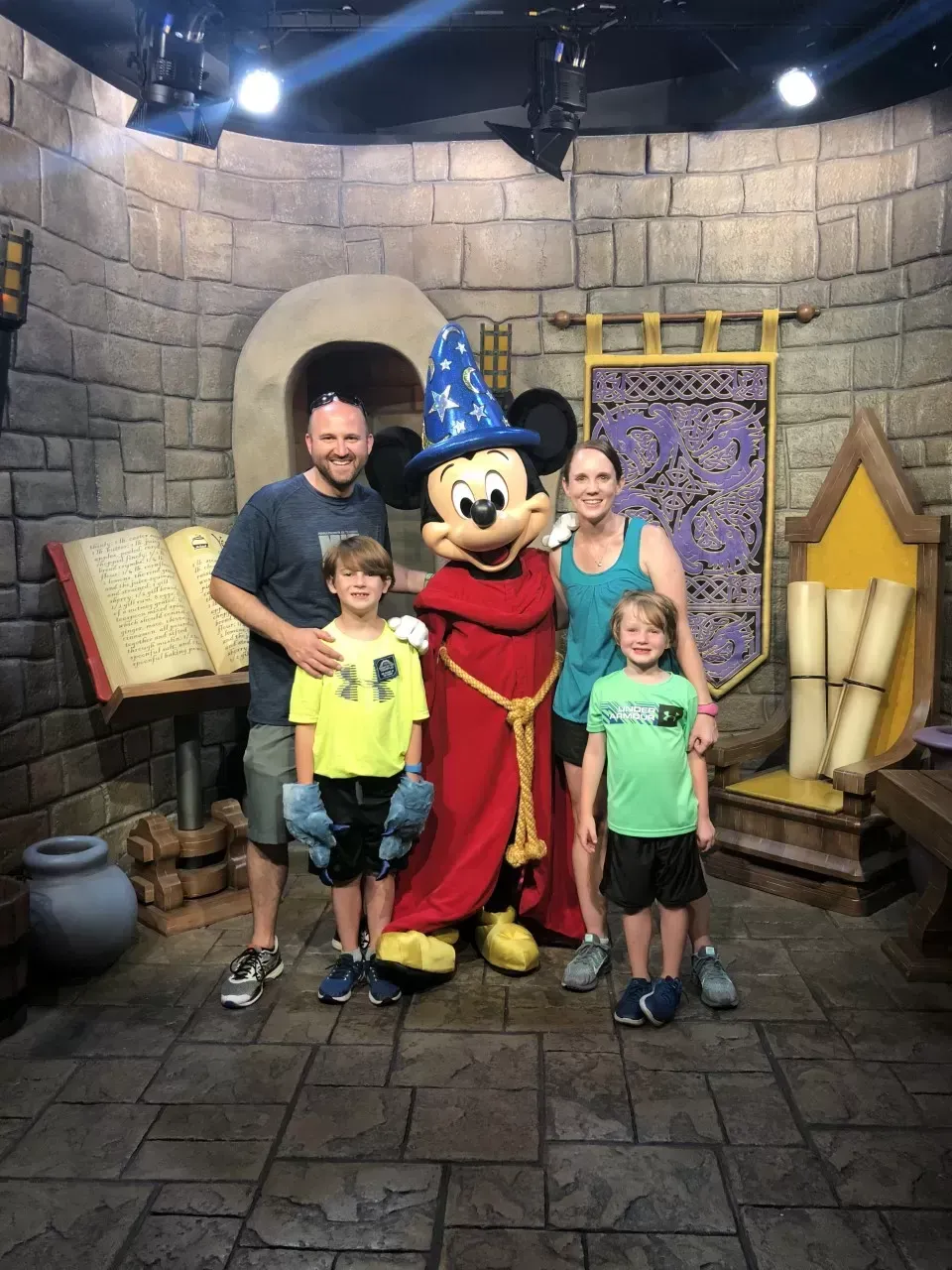 Family poses with Sorcerer Mickey in a medieval-themed room.
