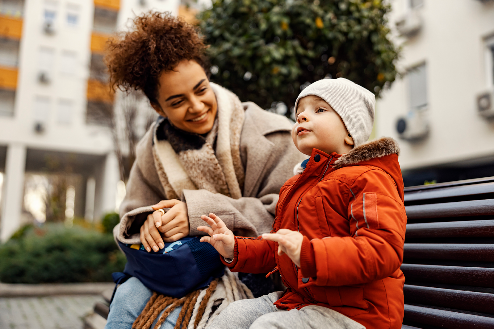 Woman and child on a couch holding cards with smiley faces. The child smiles happily.