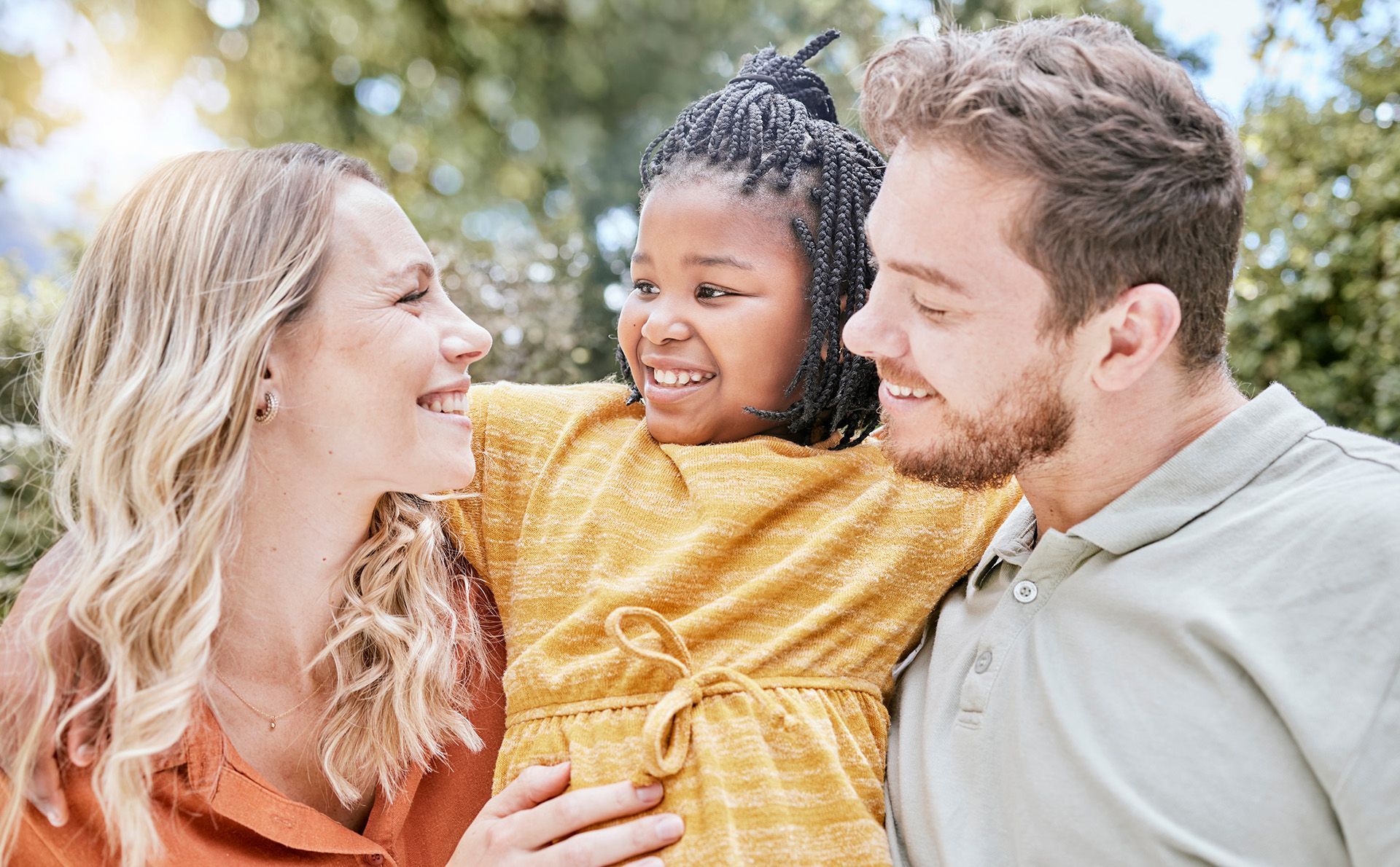 Woman and boy packing luggage together, smiling. Yellow top, white shirt, indoor setting.