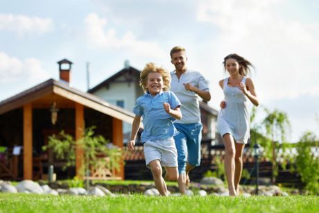 a family is running in the grass in front of a house