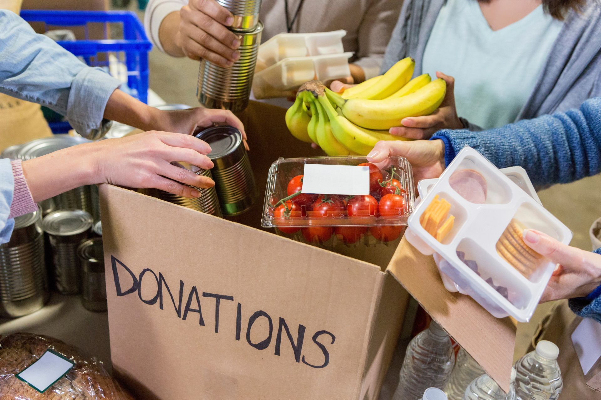 A group of people are giving food to a donation box.