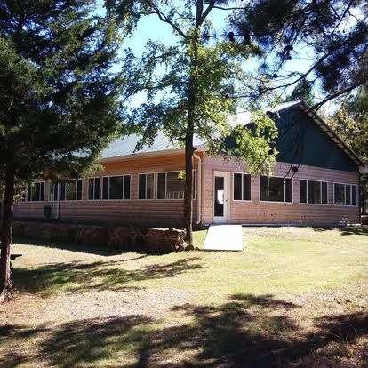 A house with a green roof is surrounded by trees