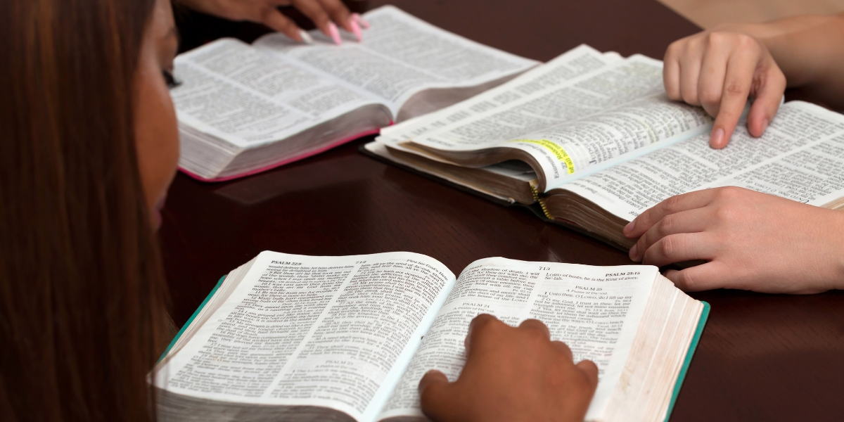 A group of people are sitting at a table reading books.