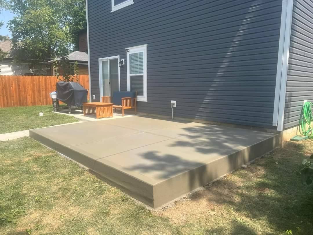 Concrete patio outside a blue house; small wooden furniture sits near sliding glass doors.