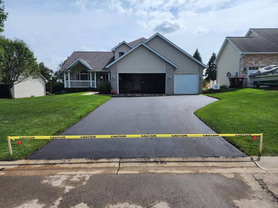 Newly paved driveway in front of a house, blocked by caution tape.