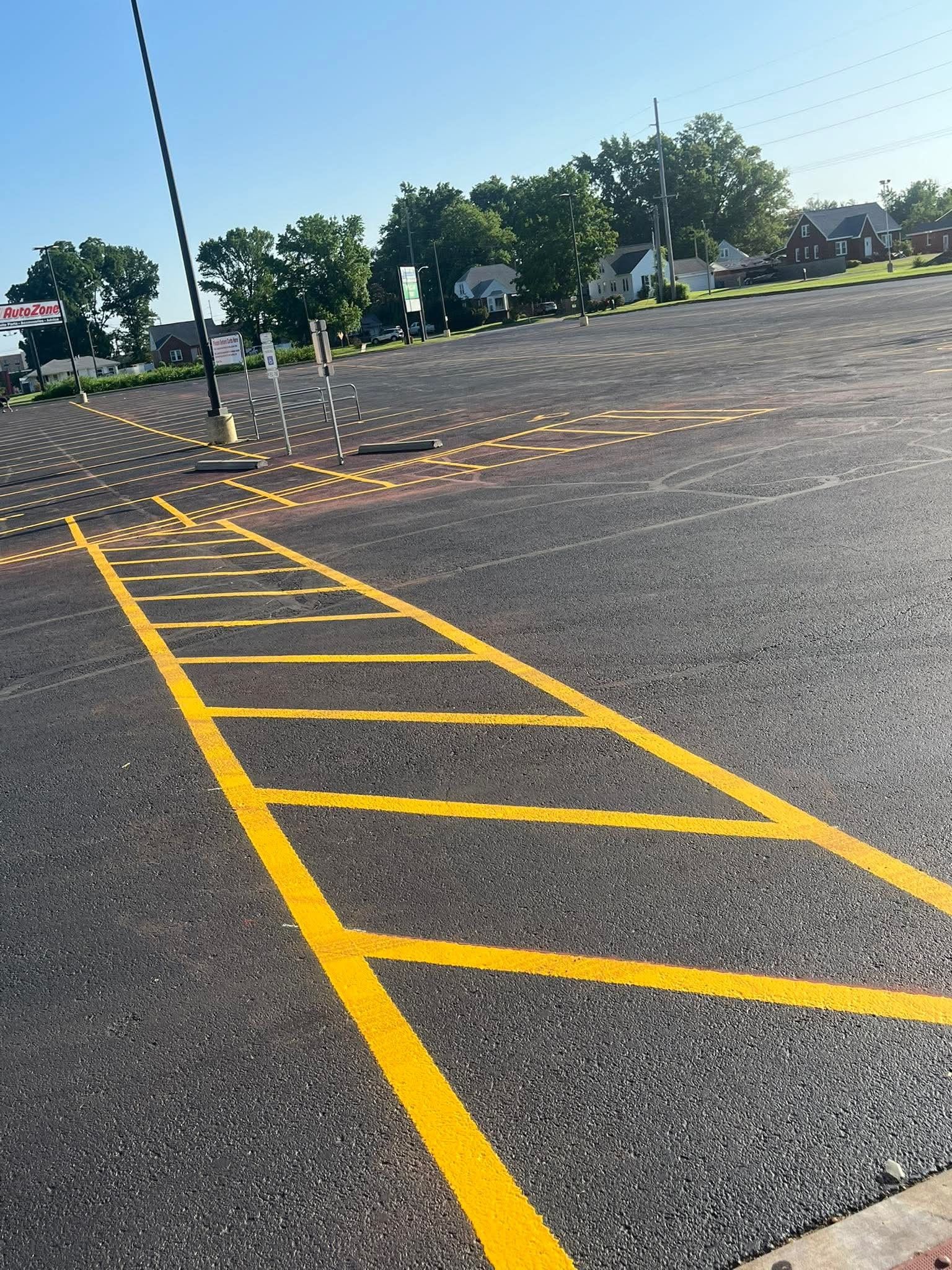 Yellow painted ladder-like markings on asphalt with reflective yellow dots, likely a crosswalk in a parking lot.