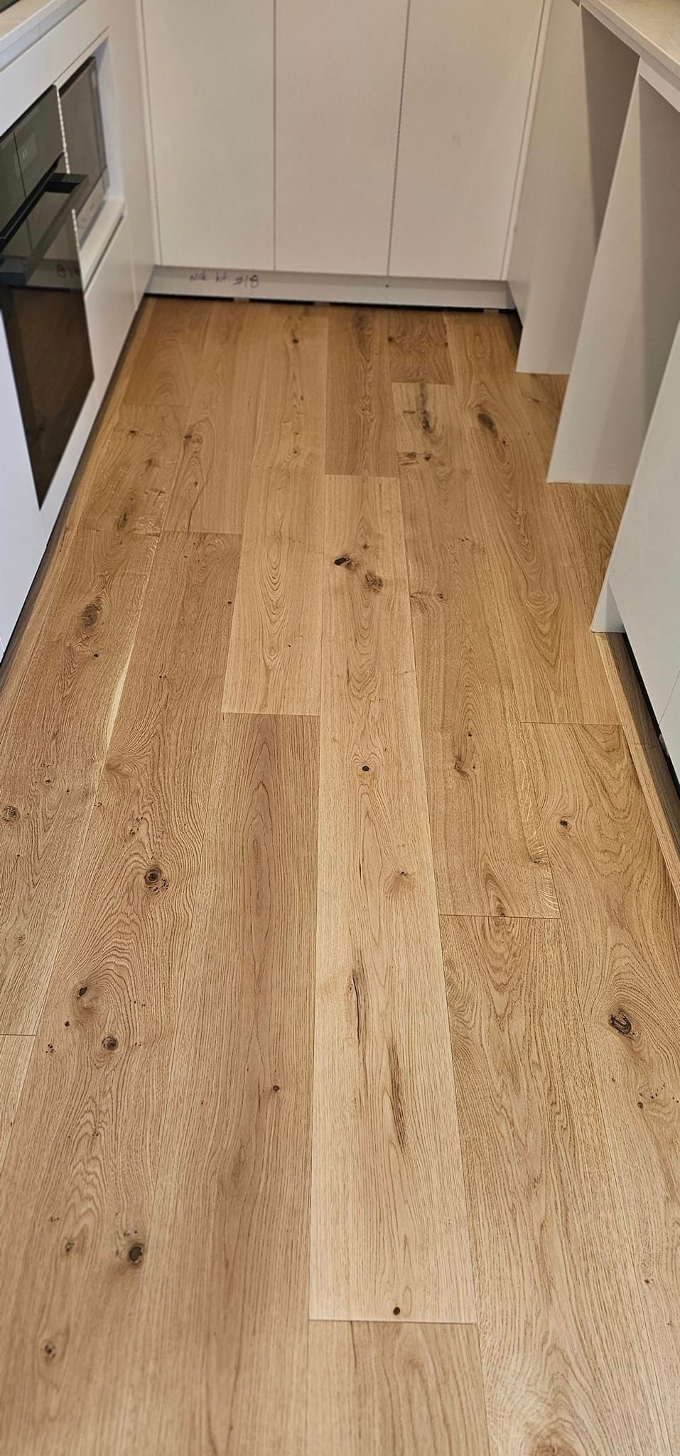 A kitchen with a wooden floor and white cabinets.
