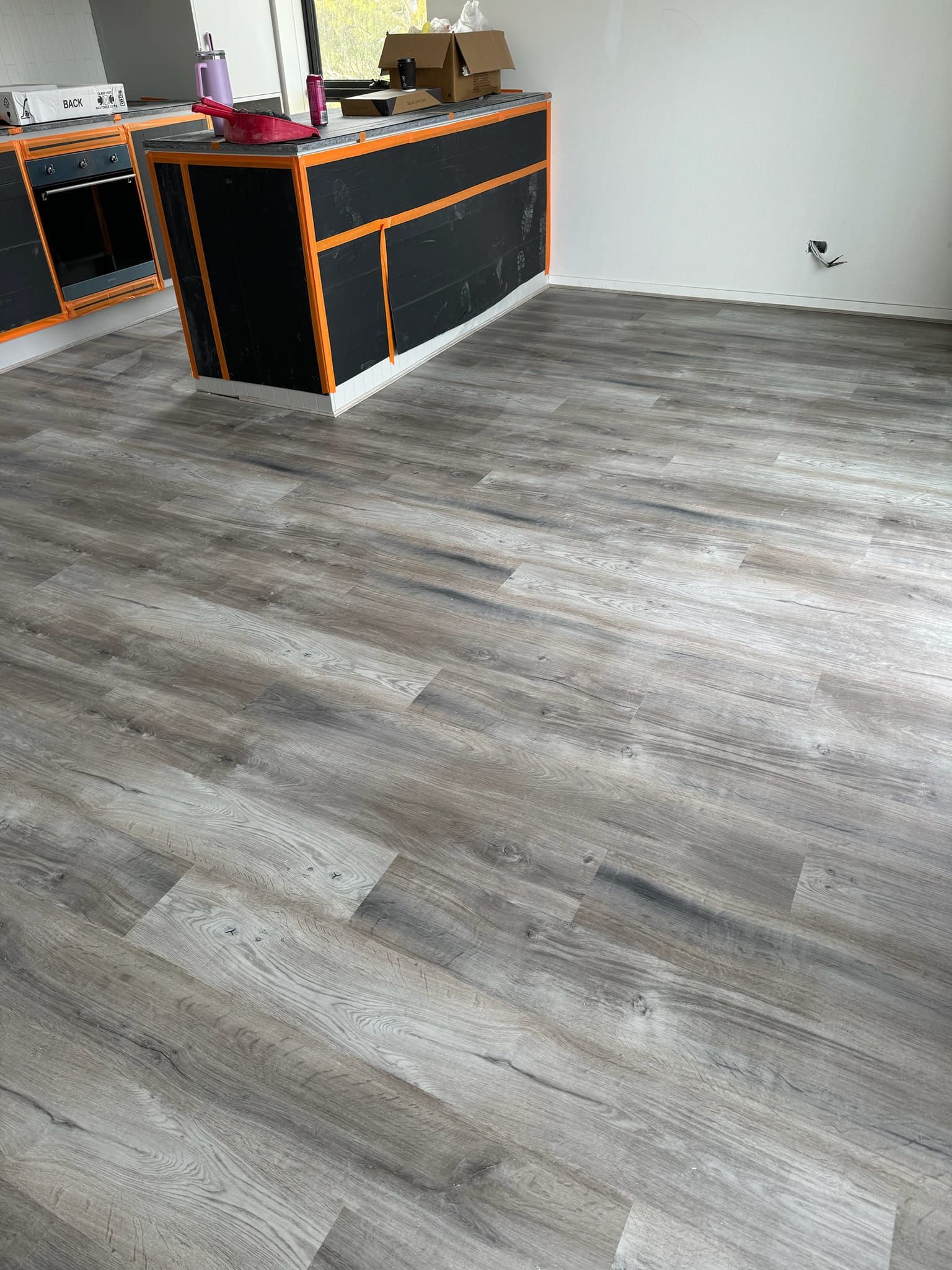 A kitchen with a wooden floor and black cabinets