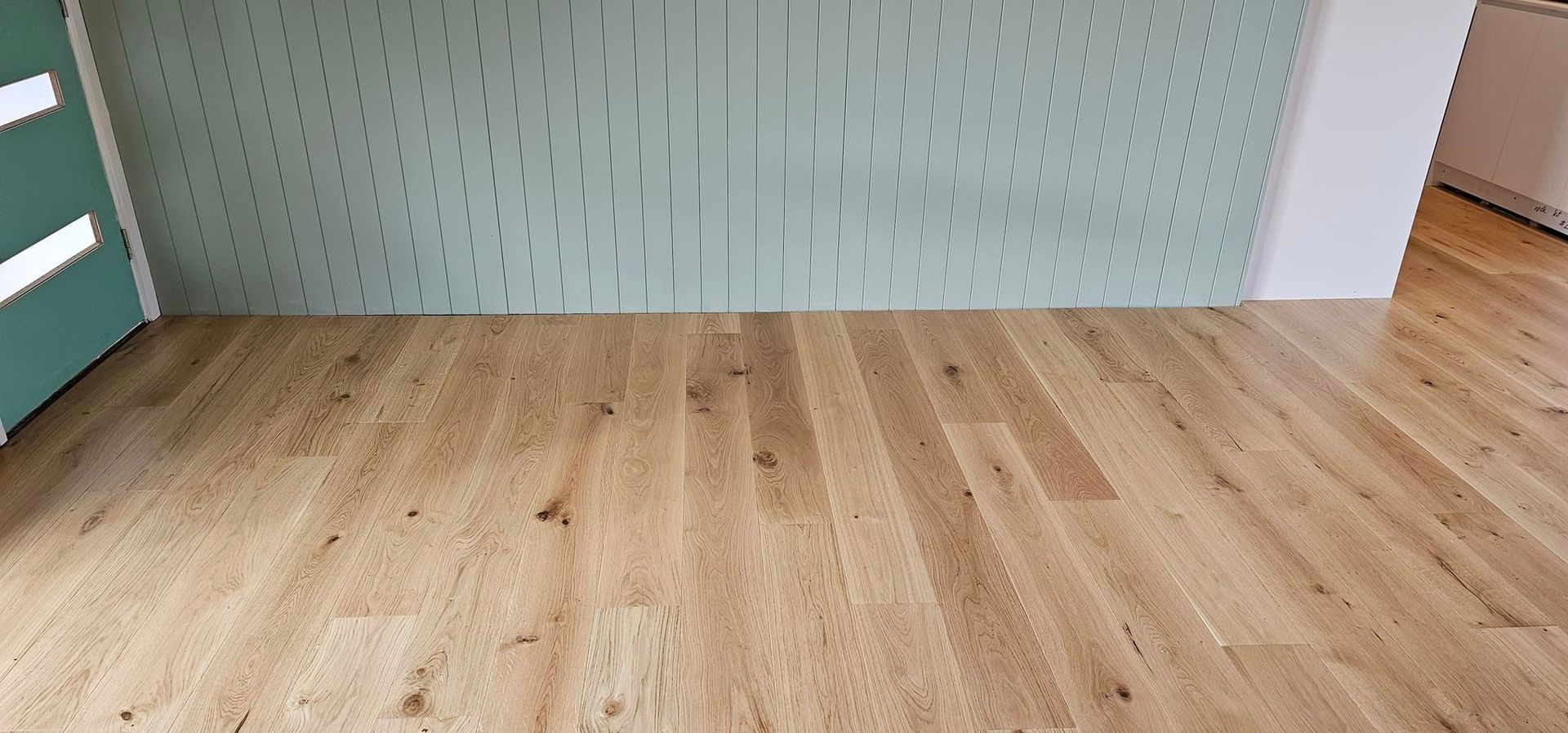 A wooden floor in a room with a green wall.