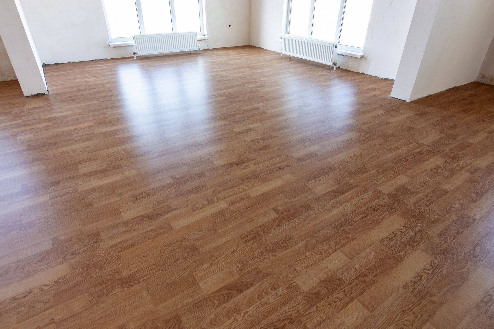 An empty room with a wooden floor and white walls.