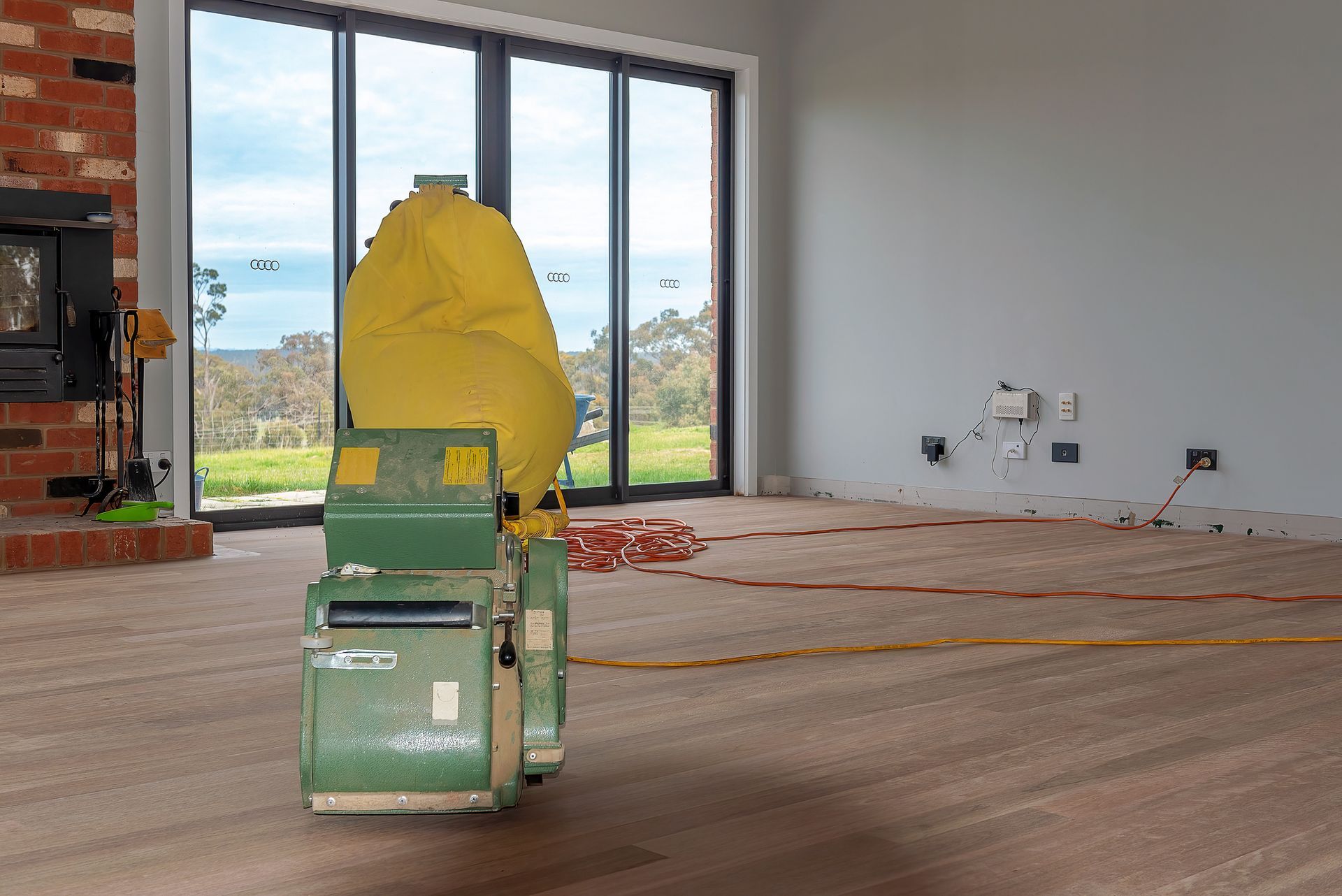 A machine is sitting on a wooden floor in an empty room.