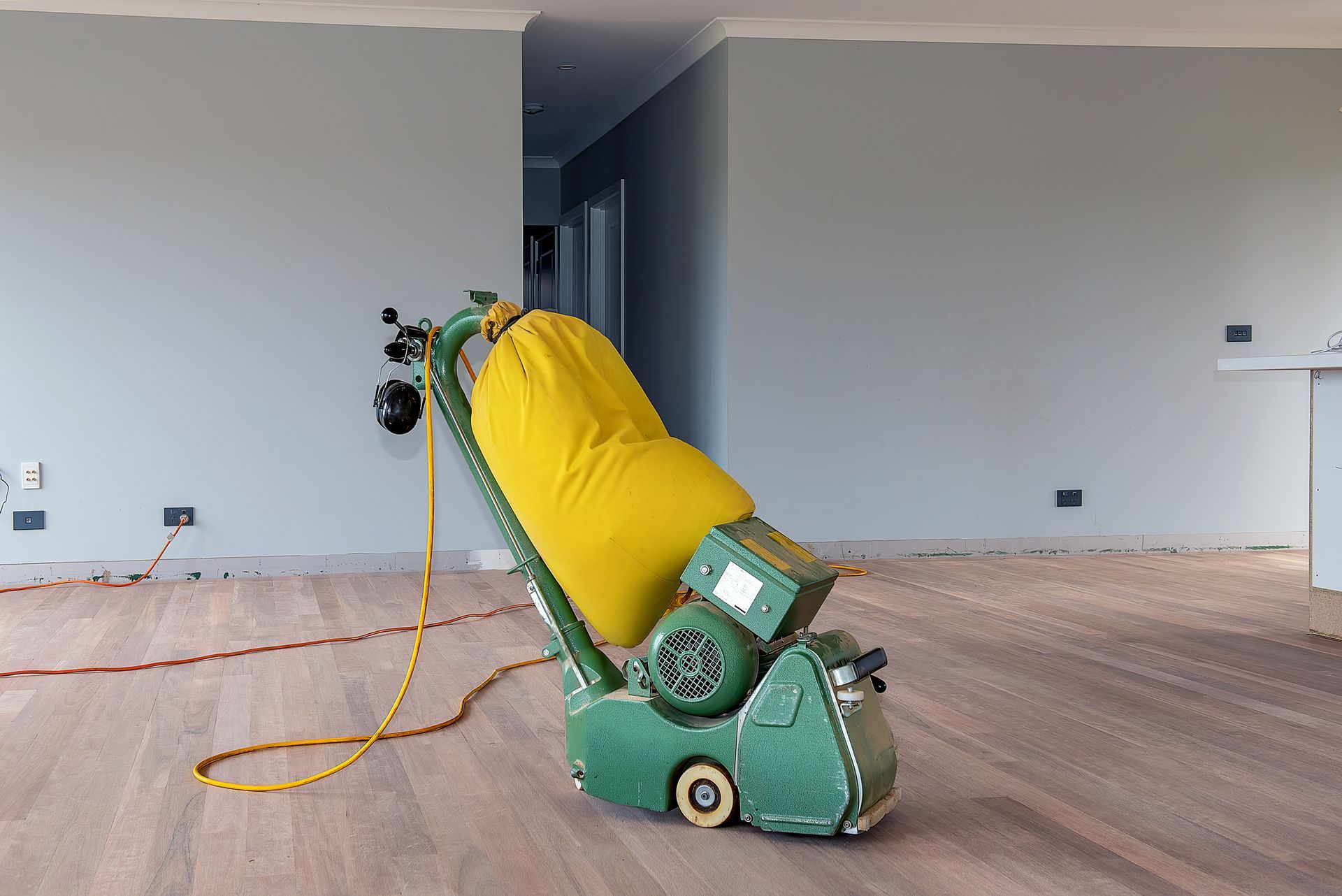 A machine is sitting on a wooden floor in an empty room.