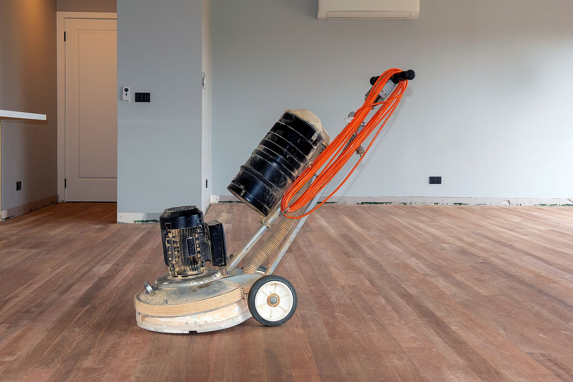 A machine is sitting on a wooden floor in an empty room.