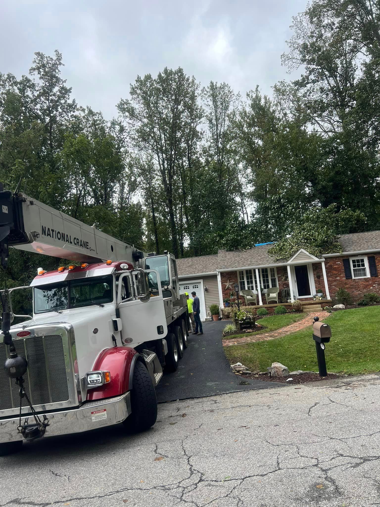 A large truck with a crane on the back is parked in front of a house.