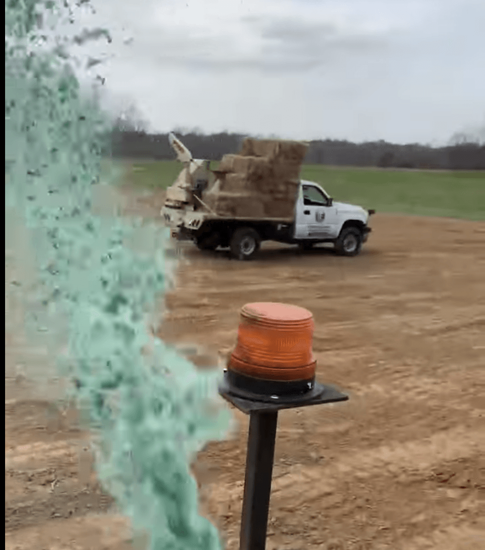 A truck is driving down a dirt road with green smoke coming out of it.