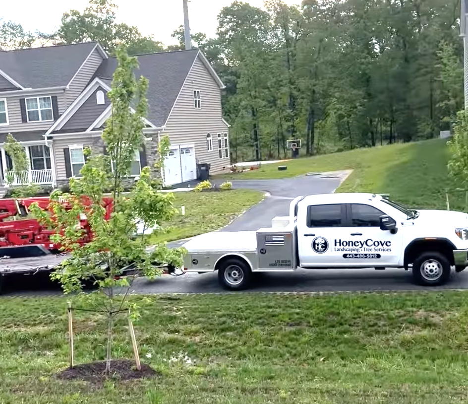 A white truck that says honey cove is parked in front of a house