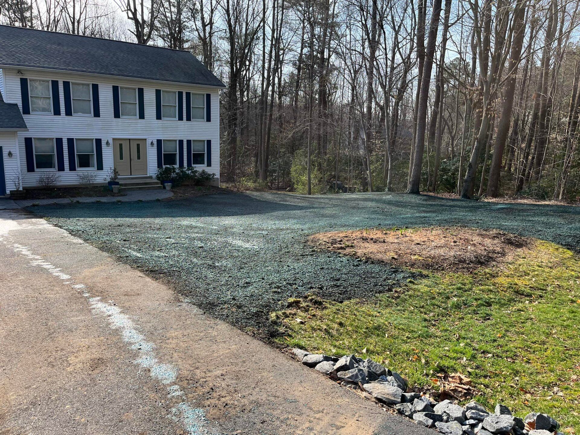A large white house with a large driveway in front of it surrounded by trees.