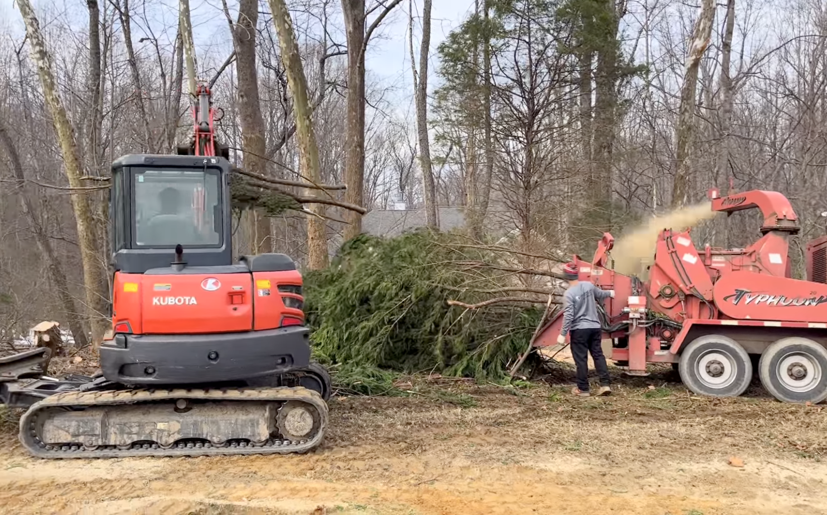 A man is standing next to a tree removal equipment.