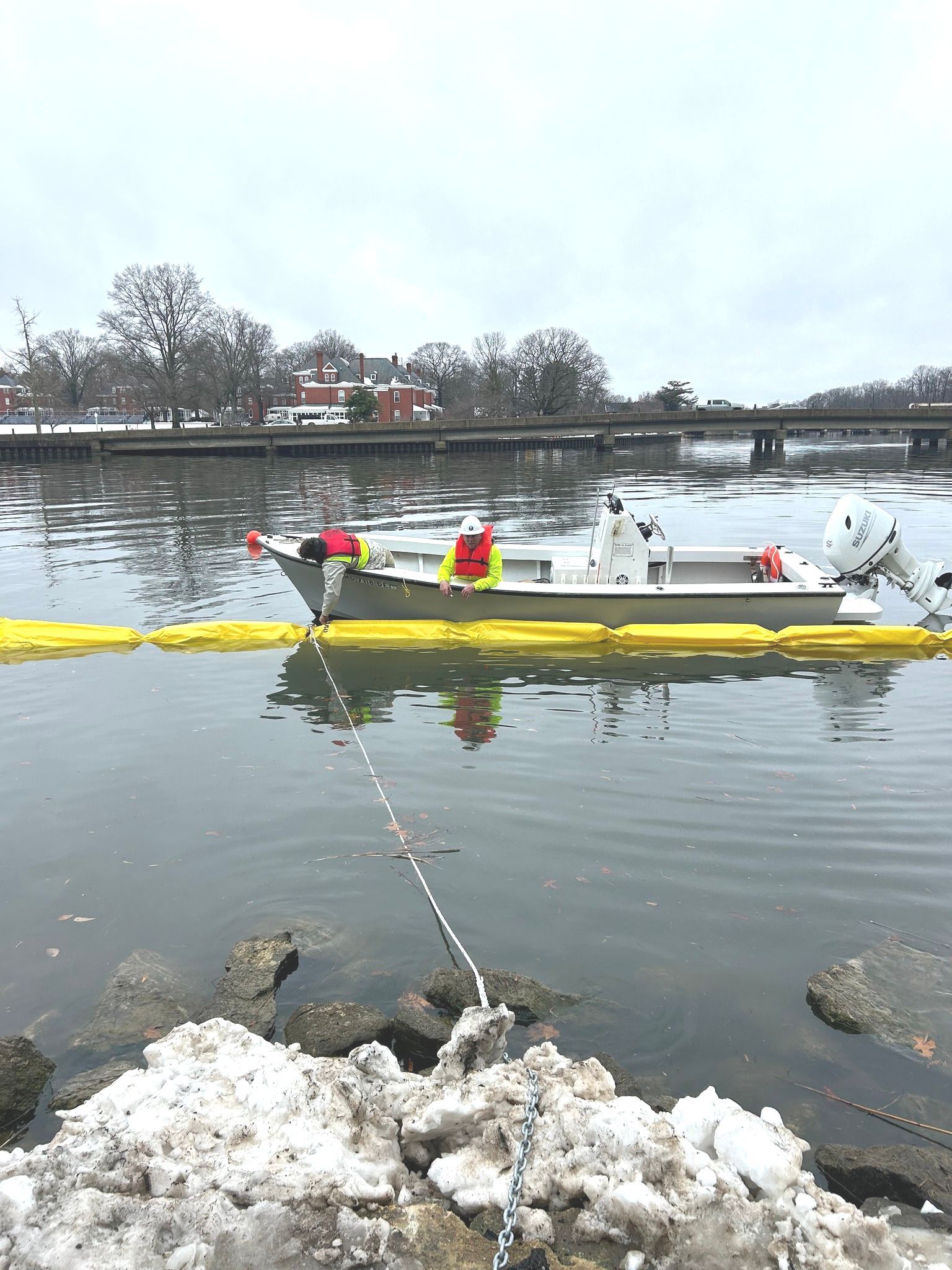 A boat is with workers is installing sediment control.