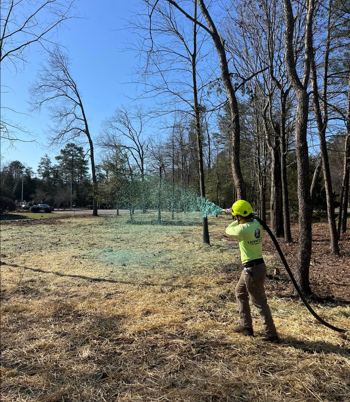 A man is spraying ground with a hose in a field to stabilize the ground.
