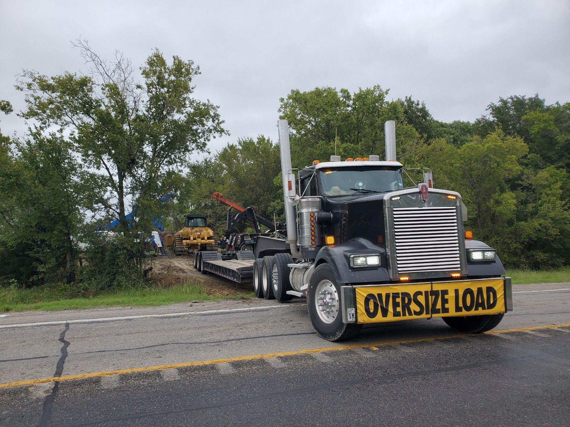 A bulldozer is digging a trench with a yellow hose attached to it.