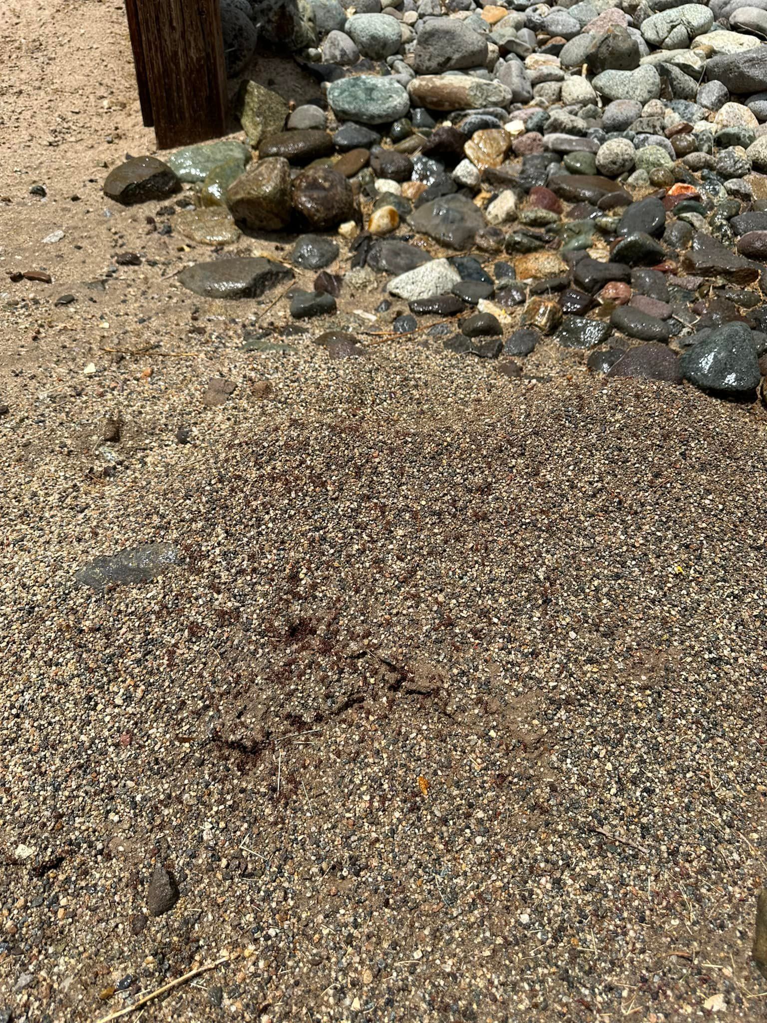 A pile of rocks and gravel on the ground next to a wooden post.