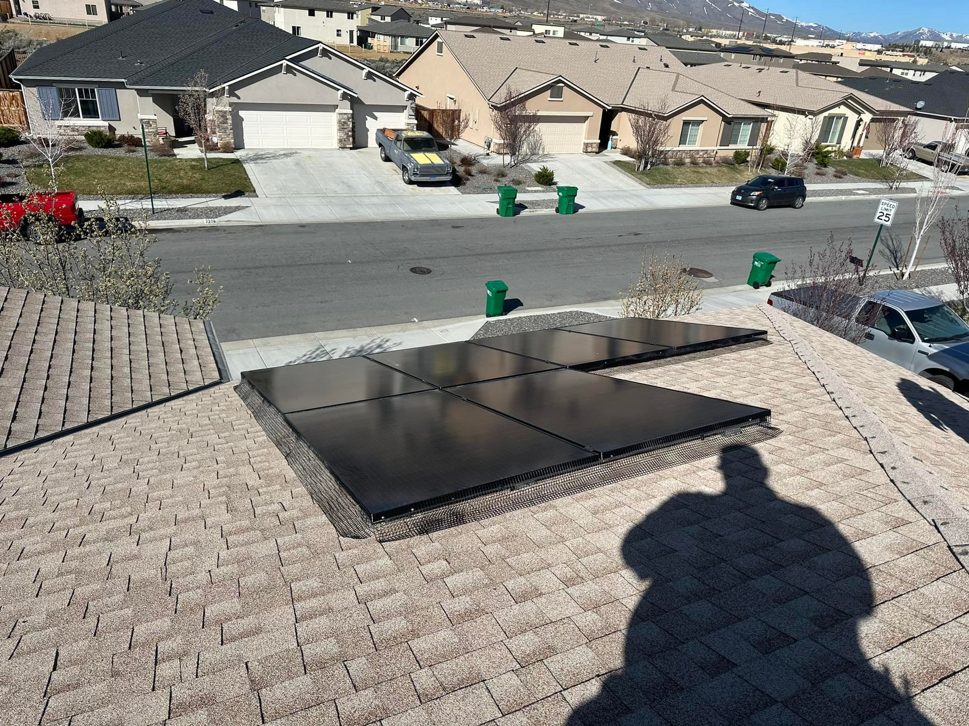A shadow of a person is cast on the roof of a house with solar panels.