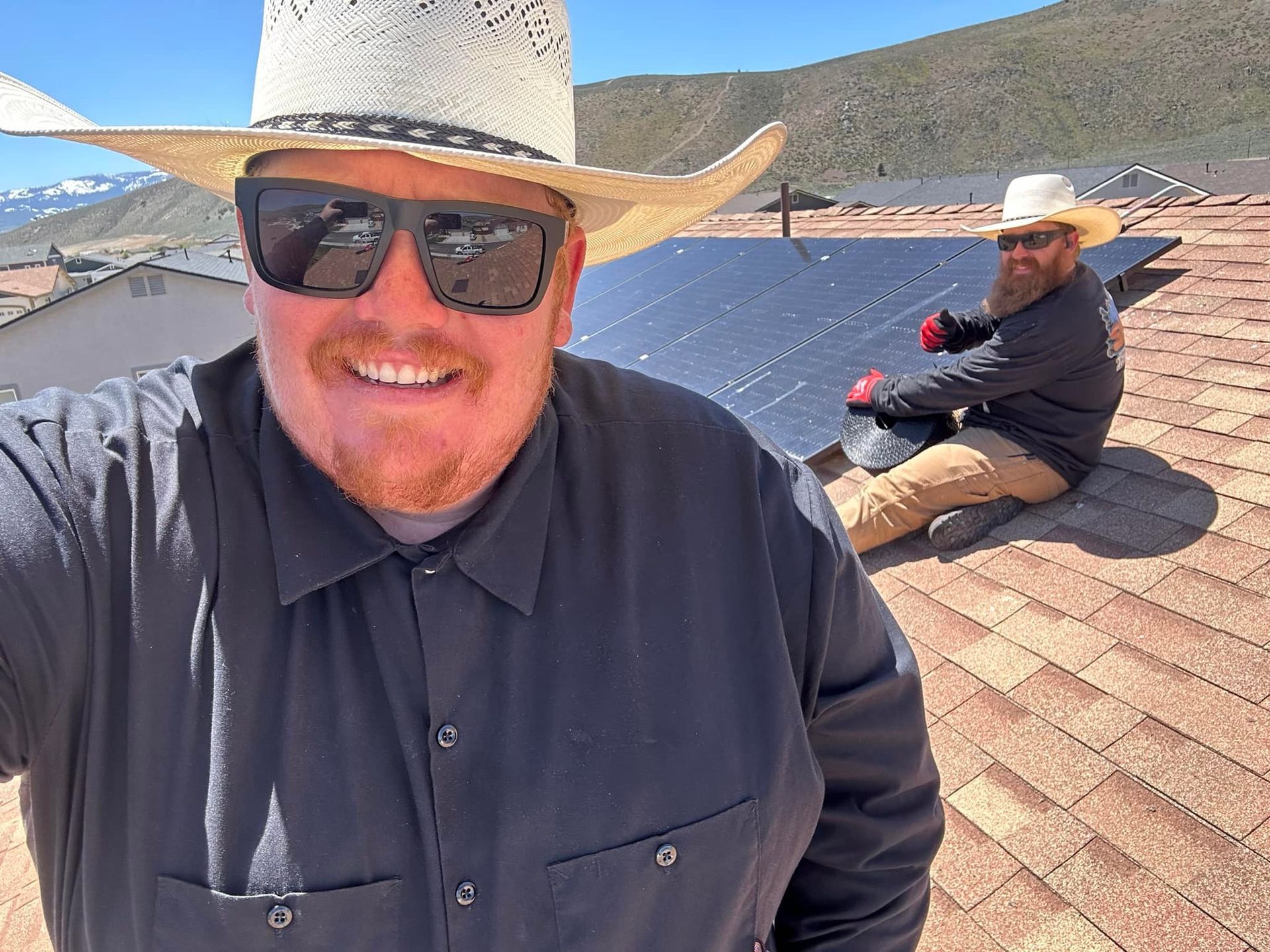 A man wearing a cowboy hat and sunglasses is sitting on a roof next to another man.